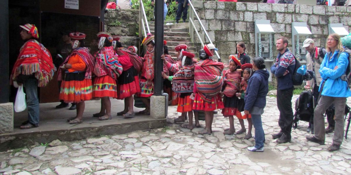 Mujeres quechuas y turistas occidentales esperando el bus a Agua Calientes
