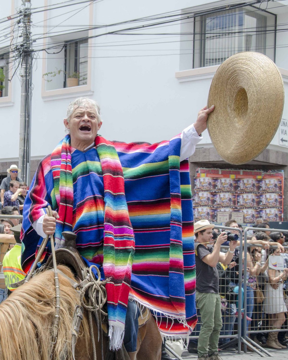 Singer in colorful poncho and doffs his straw hat as he belts out a song