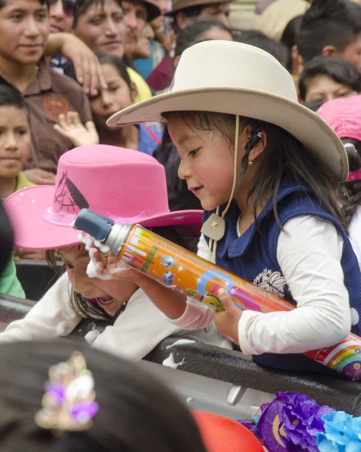No son solo los chicos a los que les gusta rociar espuma de fiesta, Guaranda, Ecuador | ©Ángela Drake Niña con lata de espuma de fiesta, Carnaval en Guaranda, Ecuador