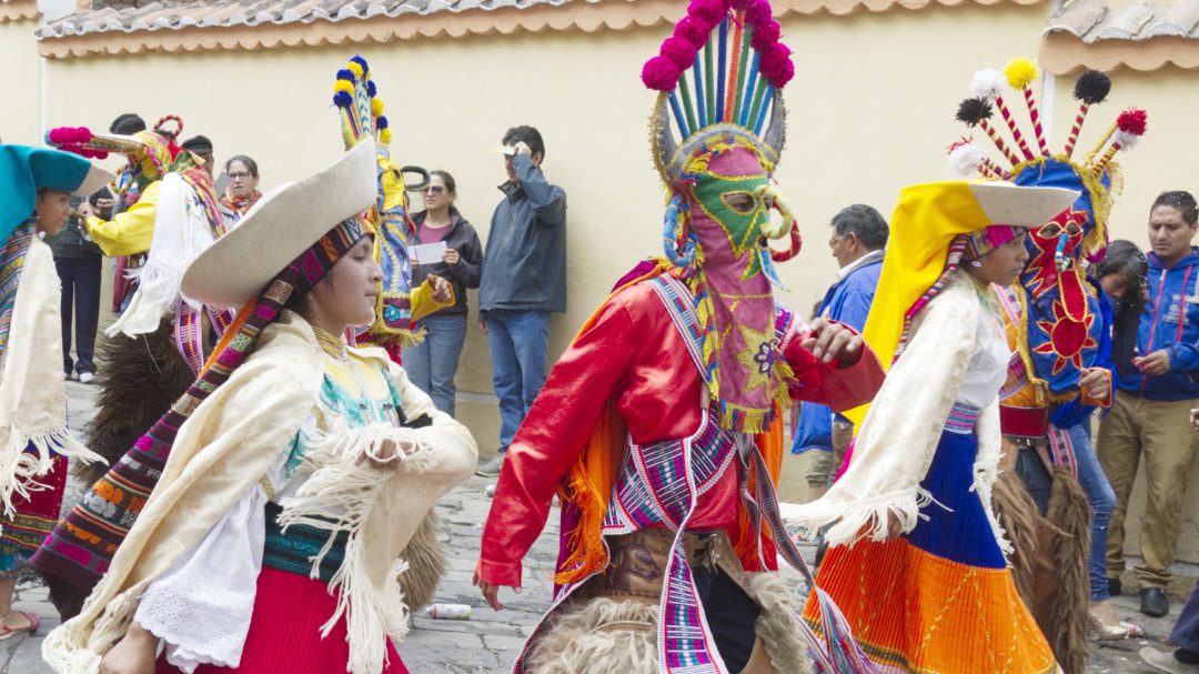 Bailarines vestidos con coloridos atuendos desfilan por las calles de la ciudad de Guamote