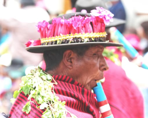 Un hombre vestido en sombrero y traje colorido tocando un instrumento de viento