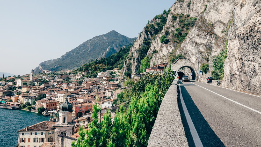 A glimpse of the stunning Lake Garda and mountainside from a road hugging a tall cliff