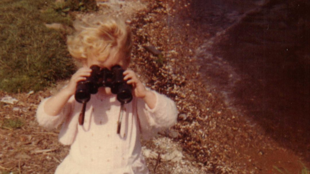 A little girl holds a pair of binoculars up to her face