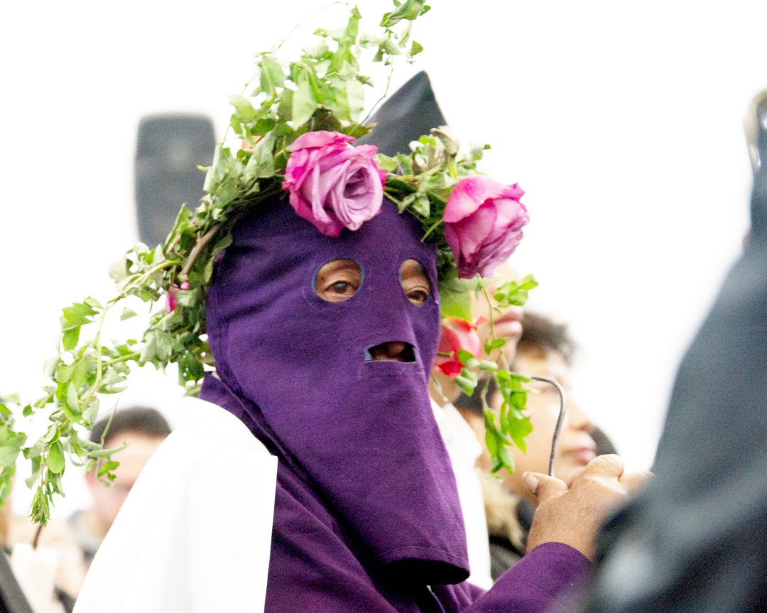 Penitente en Alangasí, Ecuador Un penitente lleva una capucha morada adornada con una corona de rosas