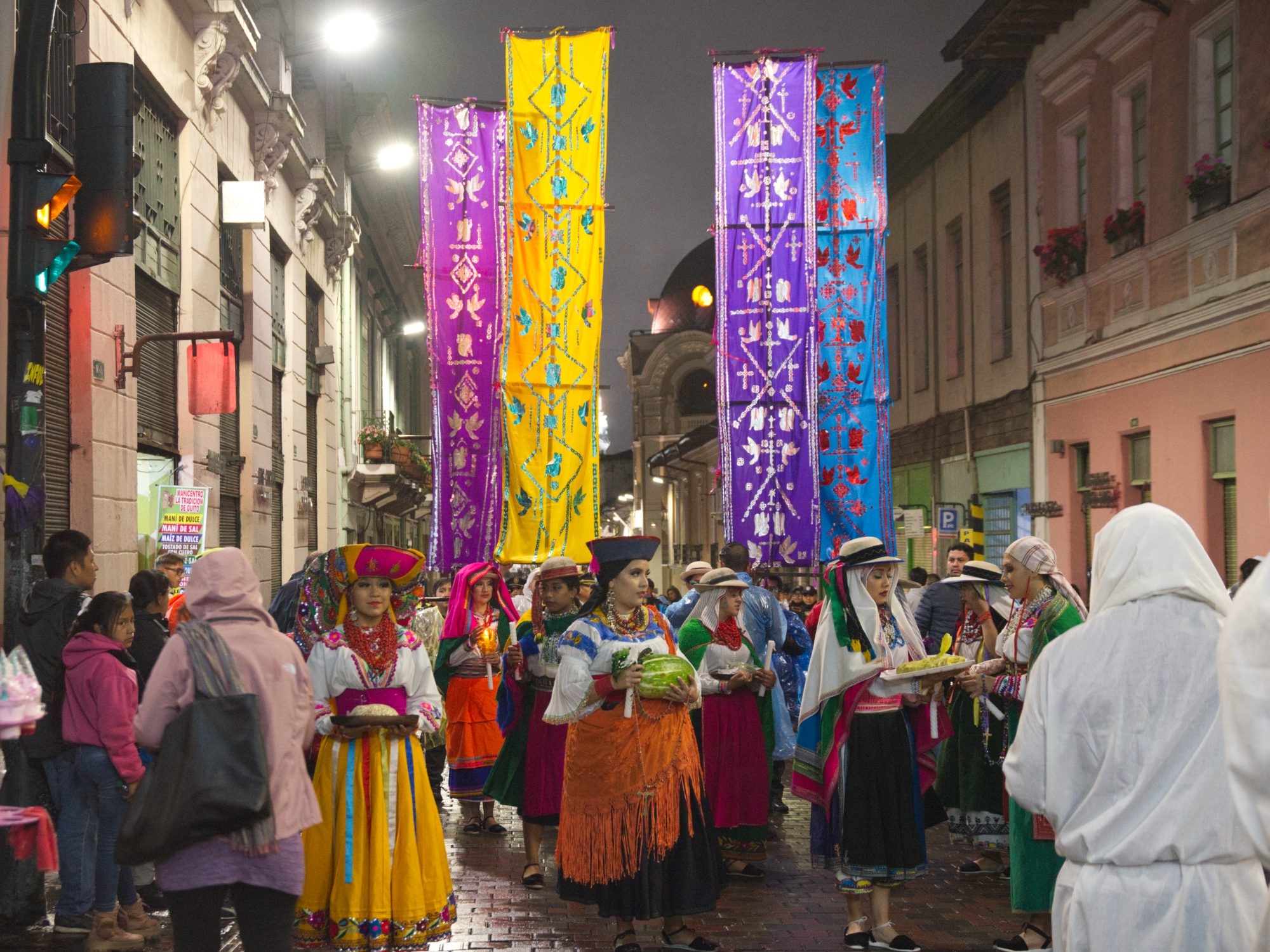 Procesión del Jueves Santo Una procesión nocturna por las calles históricas de Quito con mujeres vestidas con trajes tradicionales portando estandartes coloridos