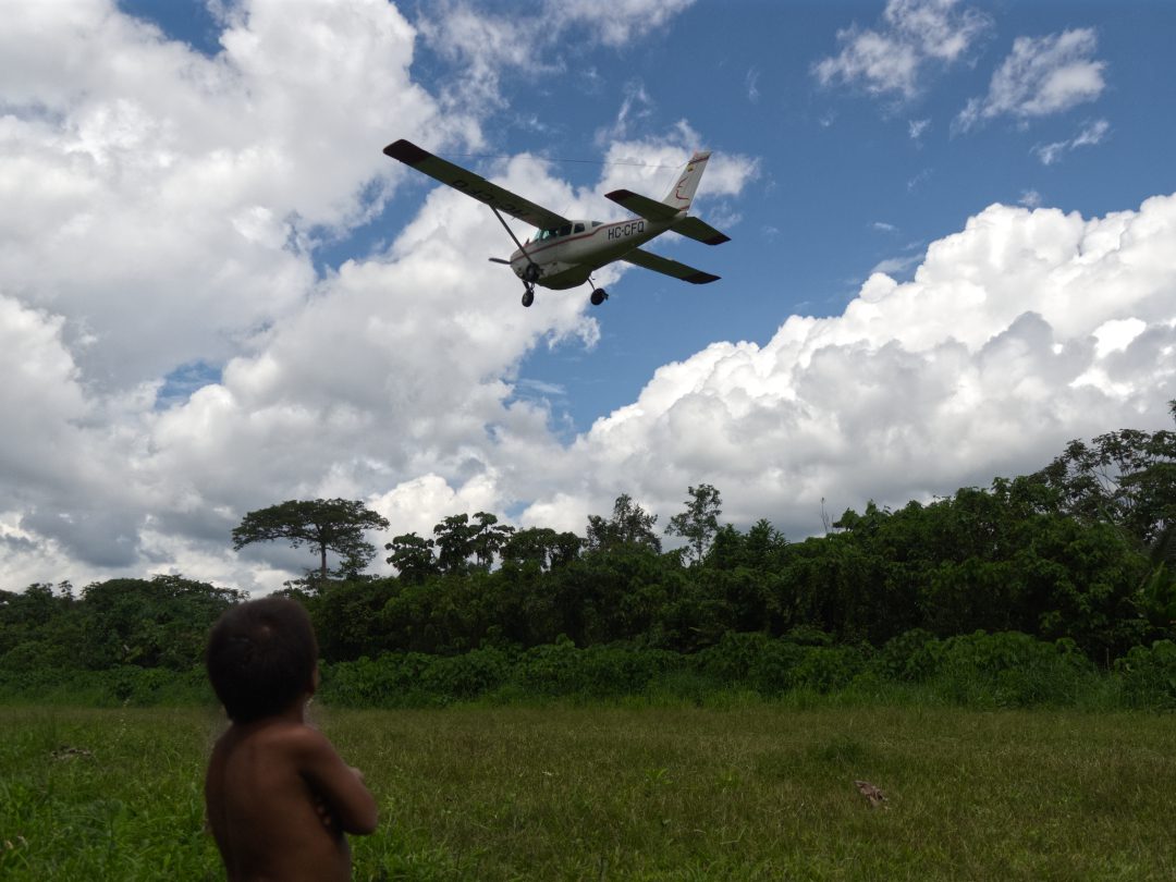 Mirando el avión | ©Angela Drake Un niño Waorani observa el despegue de un avión en la pista de hierba de Toñampare
