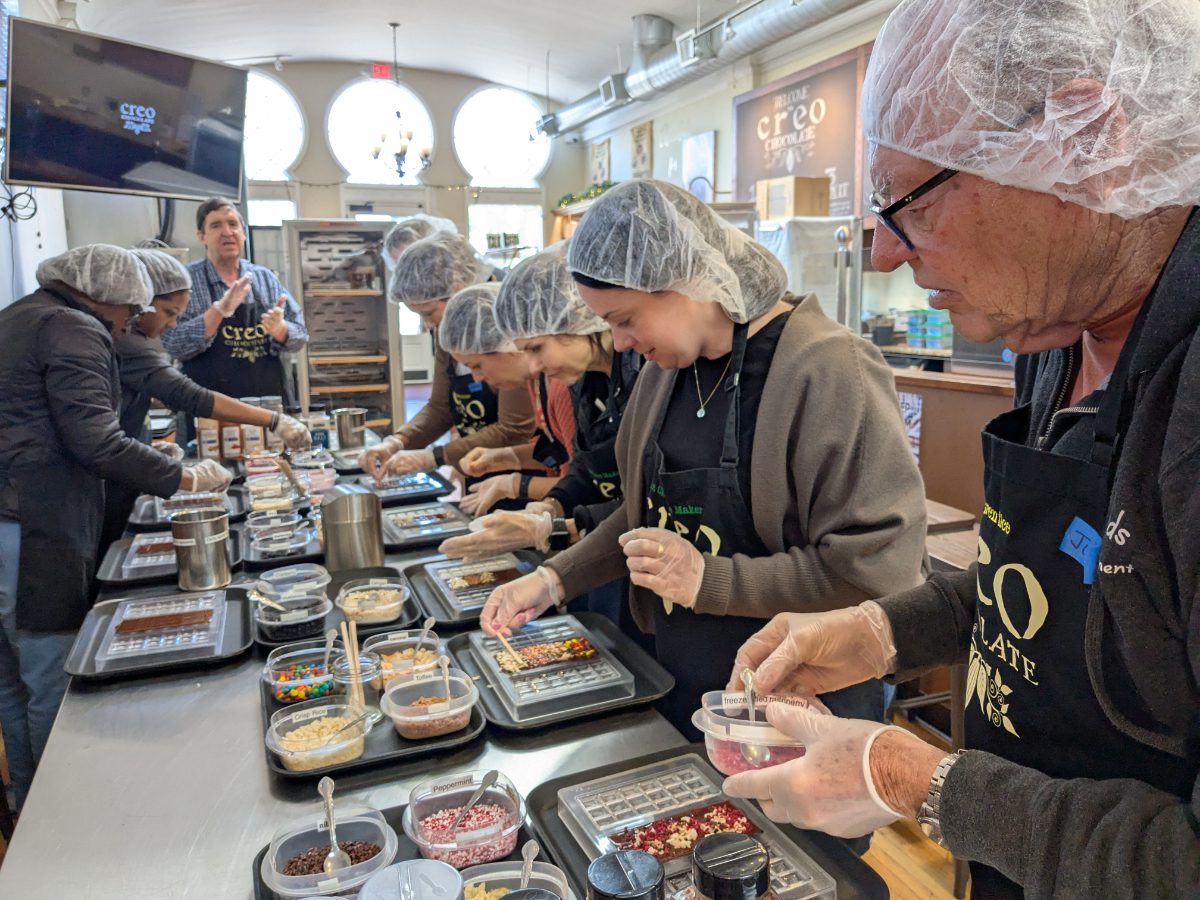 Una clase de aprendices de chocolatero trabajando duro para añadir ingredientes al chocolate líquido.