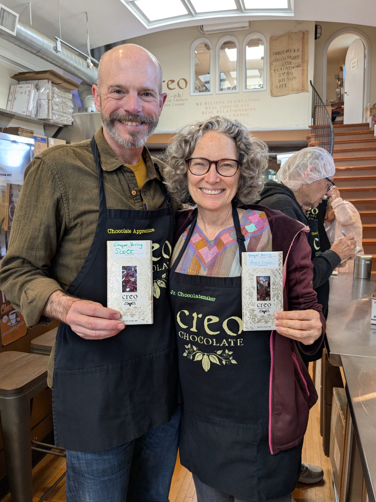 Scott y Angie con sus delantales de aprendiz de Creo sosteniendo sus tabletas de chocolate.