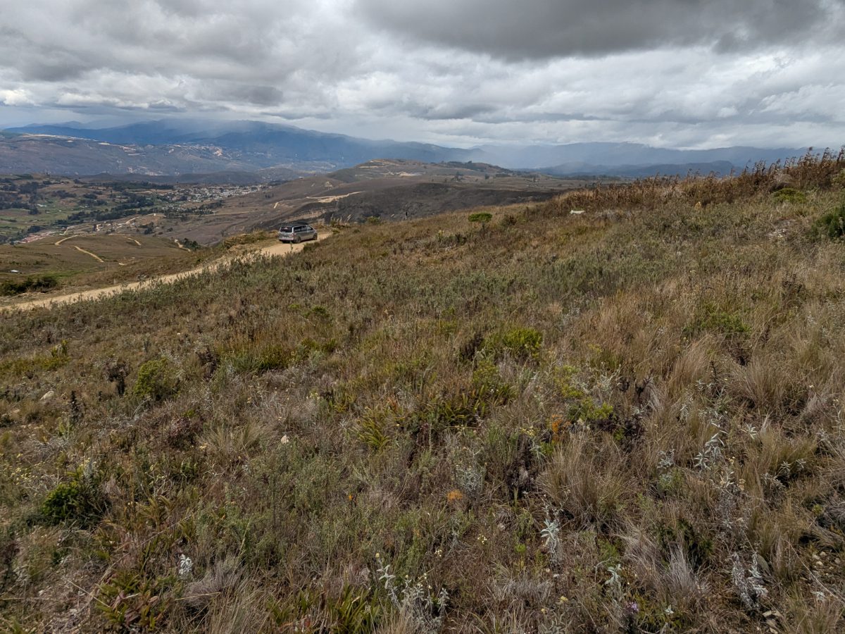 En el camino desde Cuemal, Perú Vista desde la ladera de una montaña sobre la carretera de Cuemal, Perú, con un coche aparcado en el estrecho borde de la carretera y el valle extendiéndose por debajo.